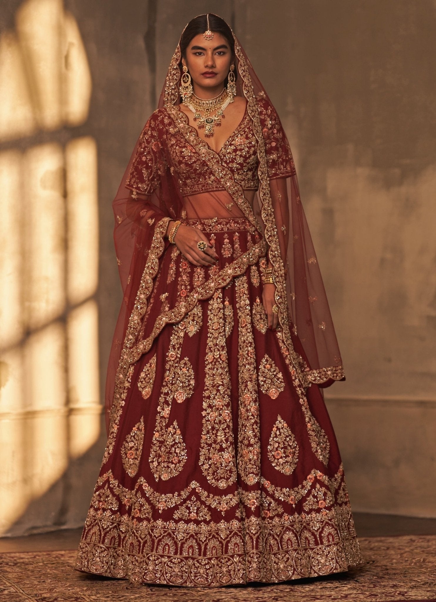 Heavily embellished maroon raw silk bridal lehenga set by Angad Singh
